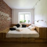 מיטה בחדר קטן עם קיר לבנים