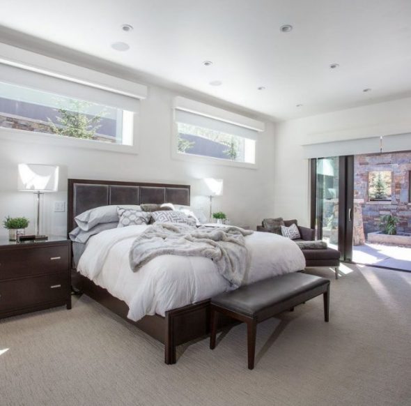 Ruime grote en lichte slaapkamer met glazen deuren en smalle ramen.