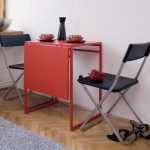 Piros összecsukható asztal és összecsukható székek egy kis konyha számára