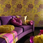 Kombinationen av lila soffa och gul tapeter