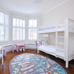 Bilik kanak-kanak dengan katil kayu putih di dua tingkat
