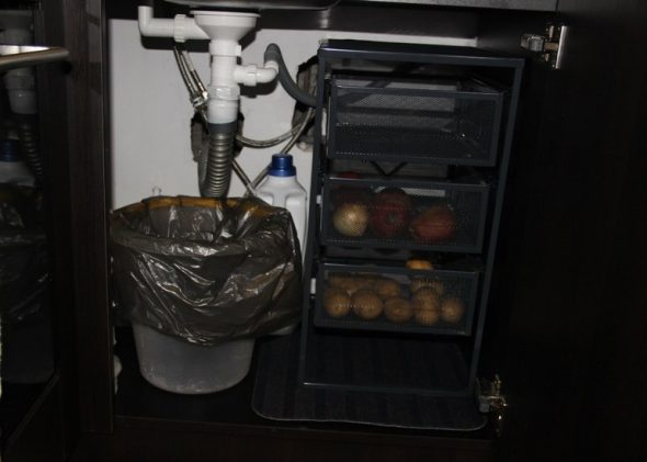 Placera för att lagra grönsaker i ett hylla under diskbänken