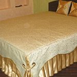 Kombination av gyllene tyg och tyg med lockar för sängkläder på sängen