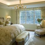 Camera da letto tradizionale con un letto alto morbido e una sedia insolita con pouf