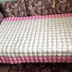 Bonbon selimut putih-merah jambu di sofa besar