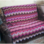 Plaid på en soffa av rester av garn, förbunden med flerfärgade zigzag ränder