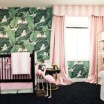Een kinderkamer met een helder accent op de muur en roze gestreepte gordijnen