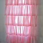 Rosa tiered gardiner på ett litet fönster