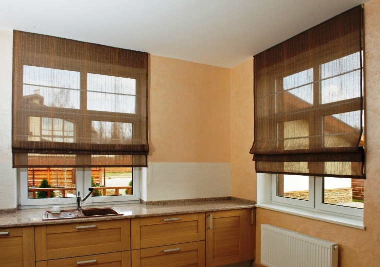 Genomskinliga syntetiska gardiner av romersk typ på kökets fönster