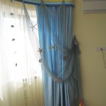 Keltainen tylli, sininen verho ja sininen koristeellinen verkko nuoren merimiehen huoneeseen