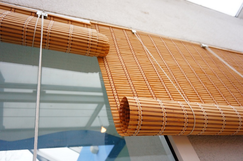 Rullade gardiner av bambu remsor på balkongen fönstret