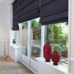 Svarta romerska gardiner på windows och dörrar i vardagsrummet med tillgång till terrassen