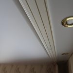 Plafond kroonlijst met bevestiging op een houten balk en verlichting in het plafond