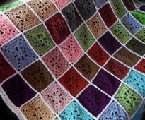Färgrika kvadrater av garnrester för en ljus pläd på soffan