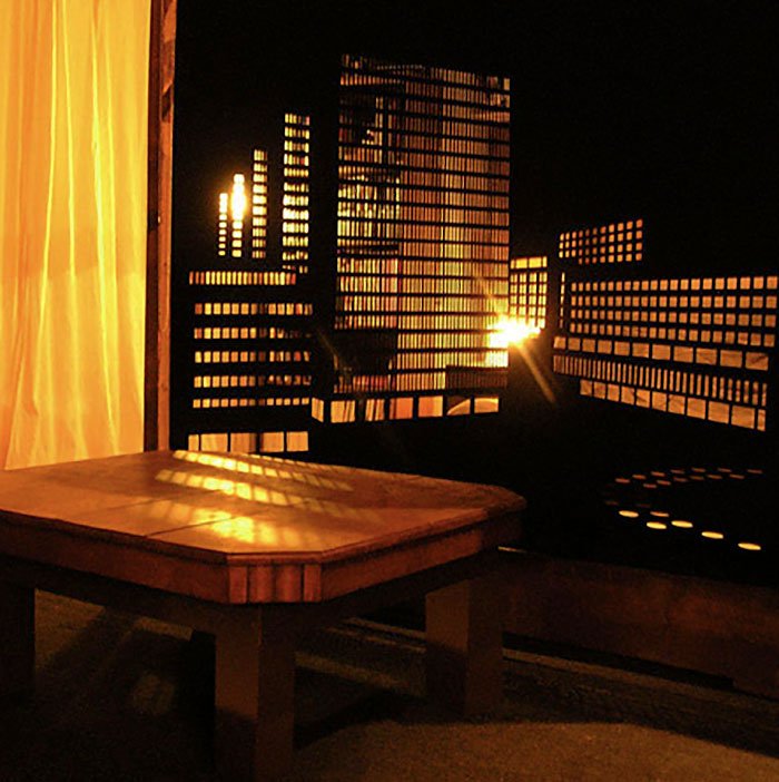 שולחן עץ ליד החלון עם וילון מחורר האפלה