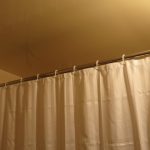 Tirai beige pada cornice langsung di bilik mandi