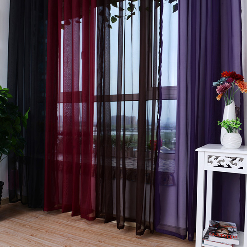 Veelkleurige tule van donkere kleuren op het raam in de woonkamer