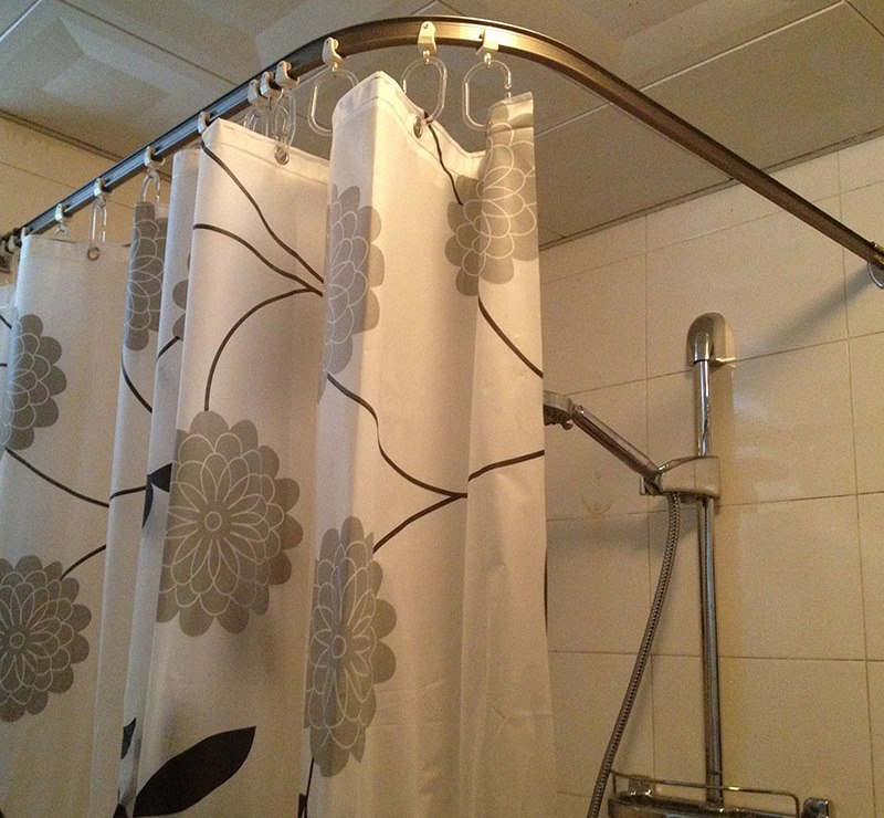 Tenda con fiori sul cornicione d'angolo nella doccia