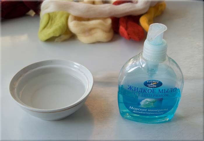 Fles vloeibare zeep en water in een kopje