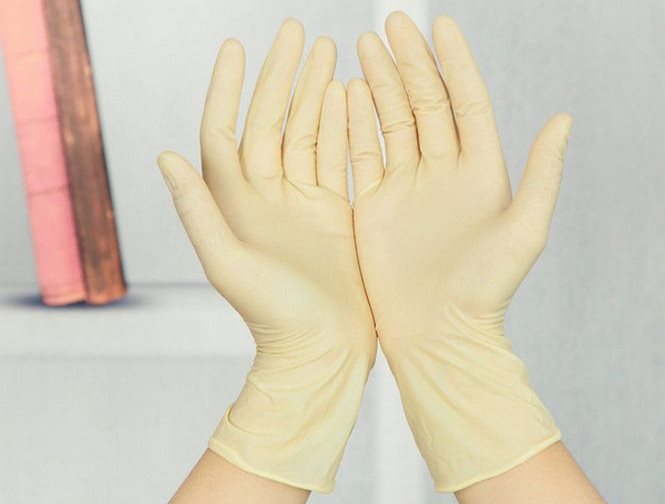 De handen van huisvrouwen in rubberen handschoenen