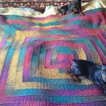 Vícebarevná deka na posteli s 10 pletenými jehlicemi