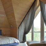 Chic gardiner på det triangulära fönstret i sovrummet på vinden
