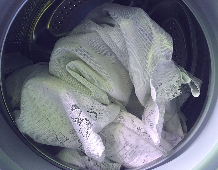 Mencuci tulle berwarna kuning dalam mesin taip