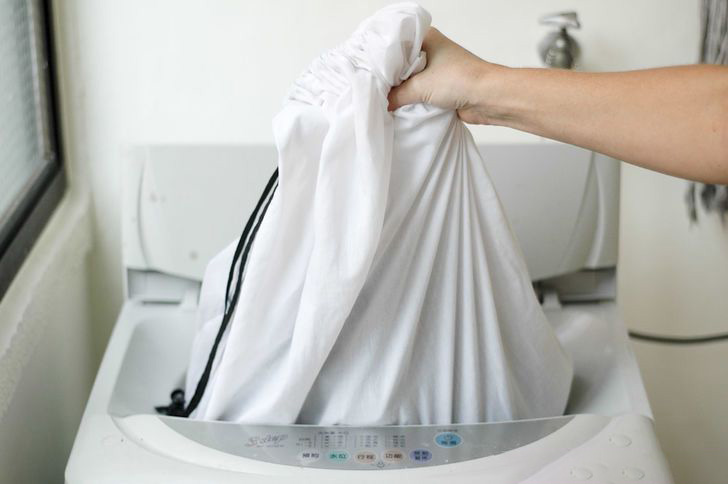 Memuatkan langsir dalam mesin dalam beg untuk mencuci