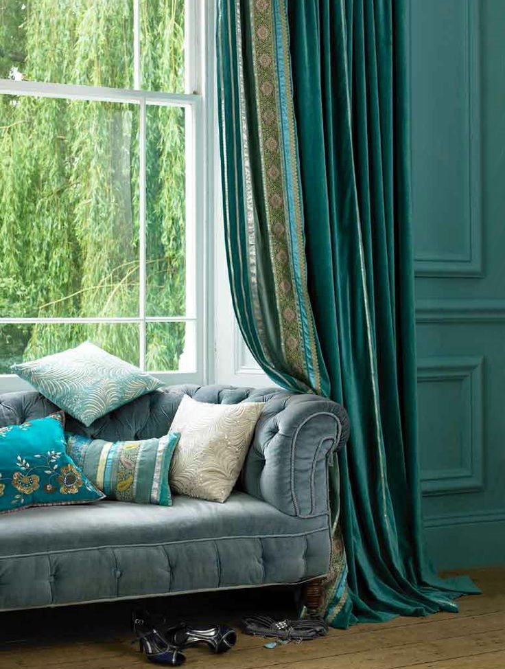 Smaragd draperier på fönstret bredvid soffan