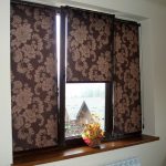 Bruna gardiner rullar typ med ett mönster på trippelfönstret