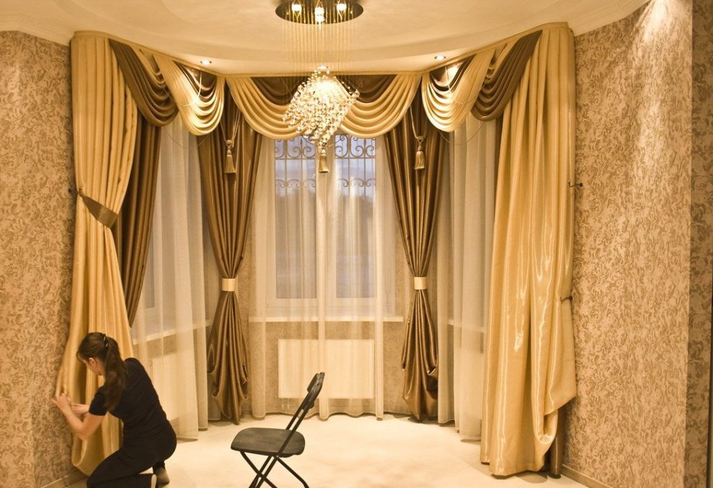 וילונות יפים עם למברקין על חלונות חלון המפרץ באולם של בית פרטי