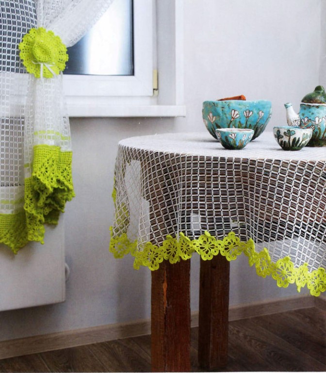 Kombinationen av stickade gardiner och dukar på ett träbord