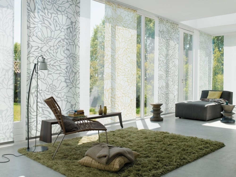Stort vardagsrum med japanska gardiner på panoramafönster.